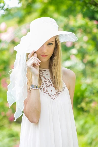 Portrét krásné přírodní mladé ženy s bílým kloboukem v růžové zahradě — Stock fotografie