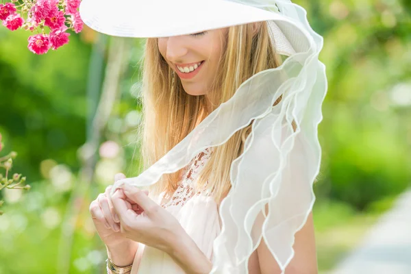 Portrait de belle jeune femme naturelle avec chapeau blanc dans la roseraie — Photo