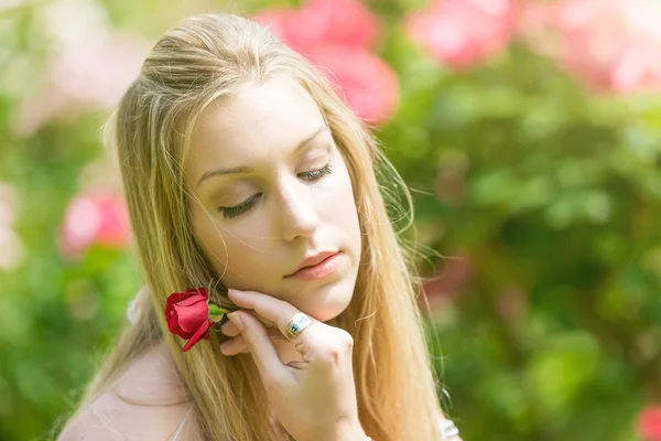 Portrét krásné přírodní mladé ženy držící červená růže v ruce v růžové zahradě — Stock fotografie