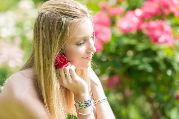 Portrét krásné přírodní mladé ženy držící červená růže v ruce v růžové zahradě — Stock fotografie