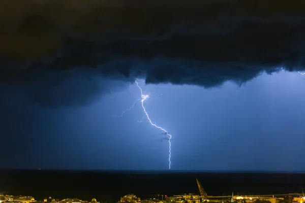 Nuvem maciça para aterrar relâmpagos atingindo o horizonte de luzes da cidade — Fotografia de Stock