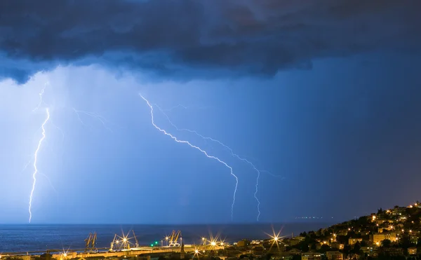 Massive cloud to ground lightning bolts hitting the horizon of city lights — Stock Photo, Image