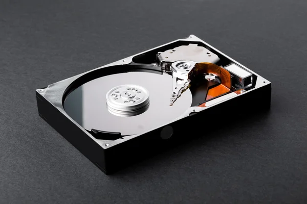 Open disassembled hard disk on black plastic background — Stock Photo, Image