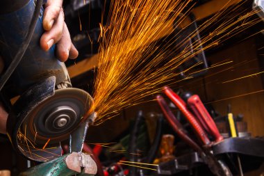 İşçi değirmeni ile metal kesme. Demir taşlama sırasında yol açtı. S