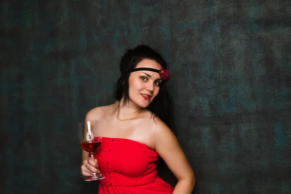 赤ワインのグラスと赤いドレスで美しいブルネットの女性 — ストック写真