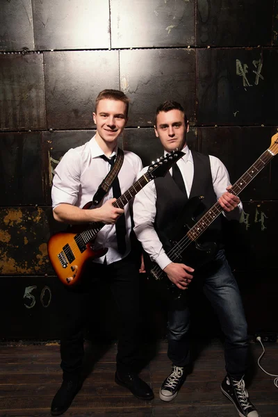 Retrato de dos jóvenes músicos con guitarra sobre fondo negro — Foto de Stock