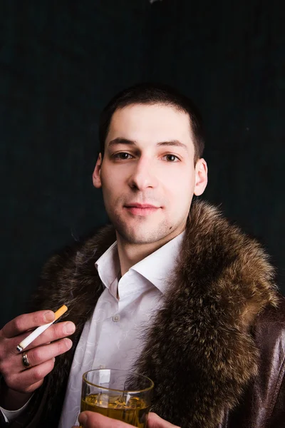 Portrait of handsome man in fur coat with glass of whiskey — Stock Photo, Image