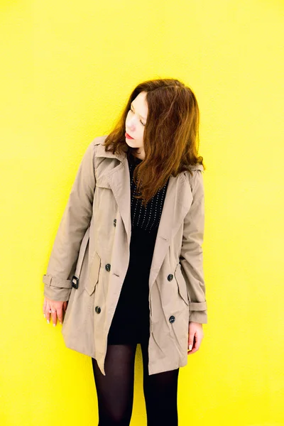 Piękna dziewczyna w płaszcz. Żółte tło — Zdjęcie stockowe