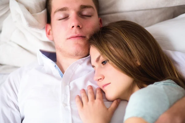 Young love couple in bed. Girl lying on the boy's shoulder