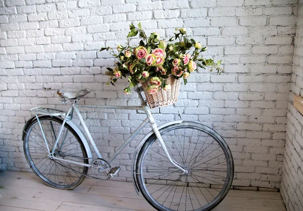 Bicicleta vieja y flores cerca de la pared de ladrillo blanco — Foto de Stock