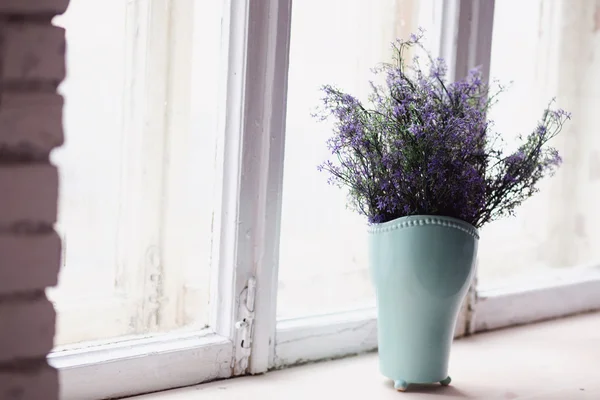 Lavender flowers are in the vase on the window of the house
