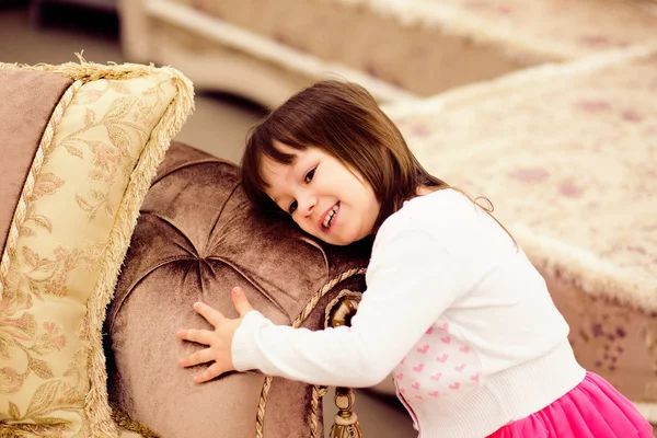 Ritratto ravvicinato di una bambina divertente che abbraccia il divano — Foto Stock