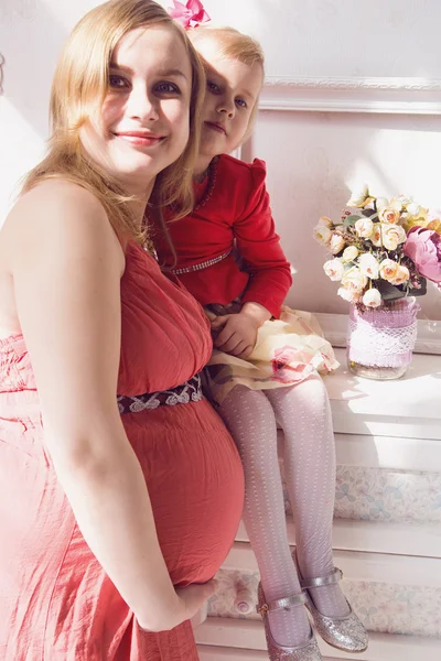Uma jovem mulher grávida bonita e sua pequena filha fofa — Fotografia de Stock