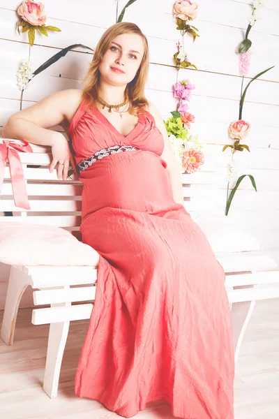 Mujer embarazada sentada en el vestido rojo — Foto de Stock