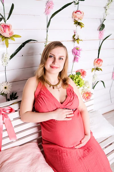 Mulher grávida sentada no vestido vermelho — Fotografia de Stock