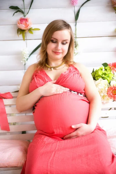 Mujer embarazada sentada en el vestido rojo — Foto de Stock