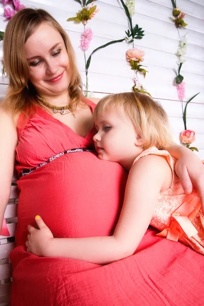 Niña abrazando el vientre de la madre embarazada — Foto de Stock