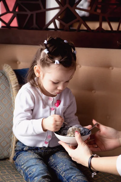 Linda menina está comendo sorvete em um café — Fotografia de Stock