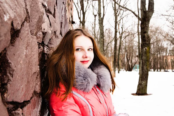 Fille dans une veste rouge sur un mur de briques — Photo