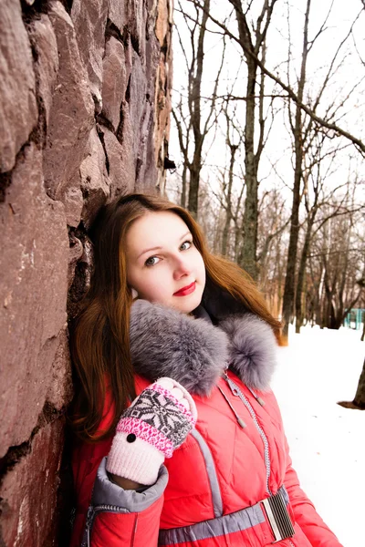 Fille dans une veste rouge sur un mur de briques — Photo