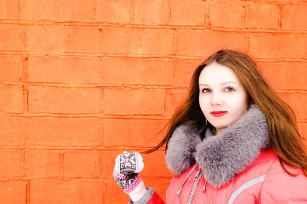 Girl in a red jacket over a brick wall — Stock Photo, Image