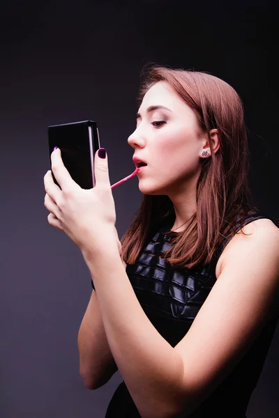 Mujer poniendo lápiz labial rojo mirando en el espejo . — Foto de Stock