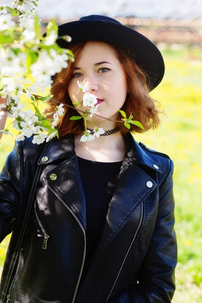 Girl in a hat enjoy spring flowers — Stock Photo, Image