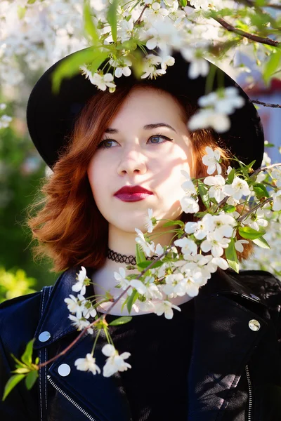 Девушка в шляпе наслаждается весенними цветами — стоковое фото