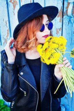 Kız bir siyah ceket ve karahindiba bir buket ile şapka