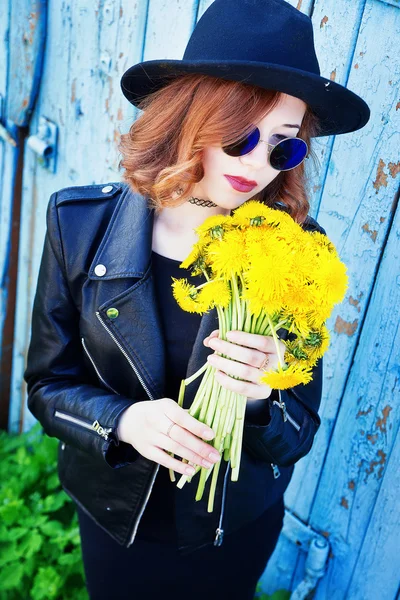 Девушка в черной куртке и шляпе с букетом одуванчиков — стоковое фото