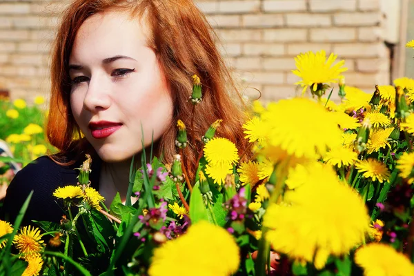 Девушка с рыжими волосами лежит на поле одуванчиков — стоковое фото