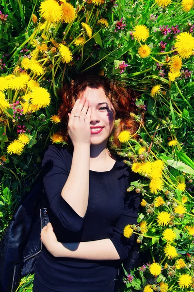 Girl with red hair lying on the field of dandelions — Stock Photo, Image