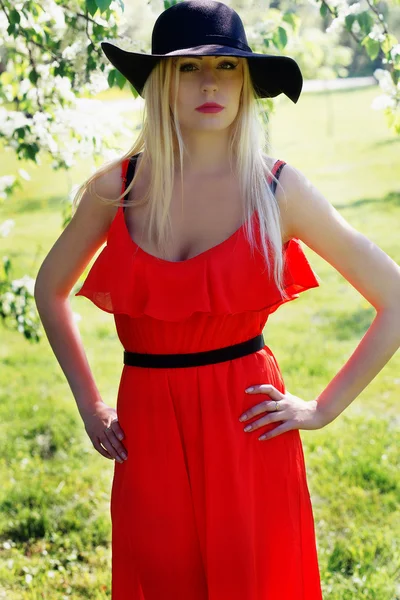 Элегантная девушка в красном платье прогулка в парке — стоковое фото
