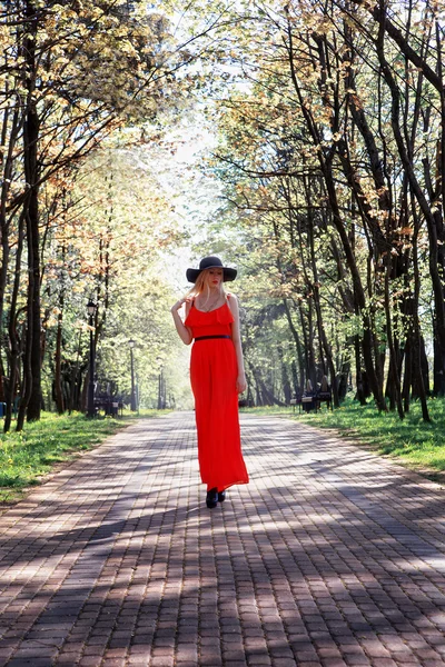 Elegant girl in a red dress walking in the park — Stock Photo, Image