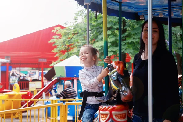 Mom and daughter in the park and ride on the carousel — Stock Photo, Image