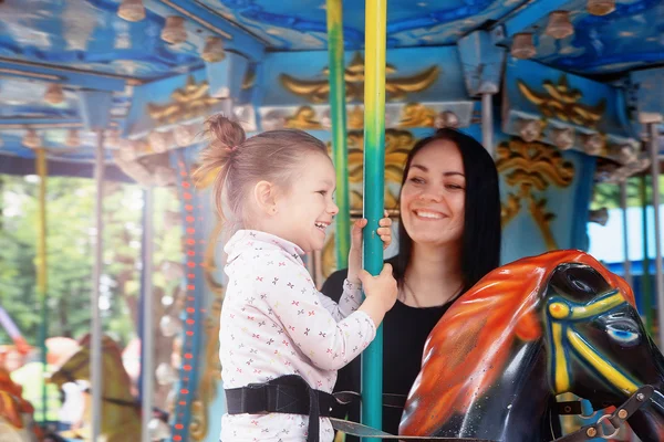 Mom and daughter in the park and ride on the carousel — Stock Photo, Image