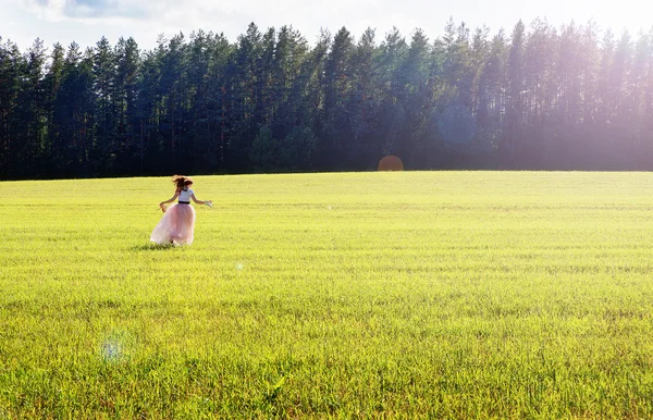Glückliches Mädchen im langen Rock läuft auf das Feld — Stockfoto