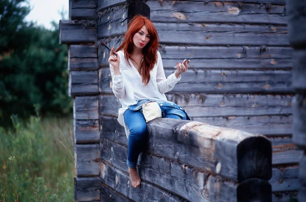 Girl in white shirt and blue jeans doing makeup — Stock Photo, Image