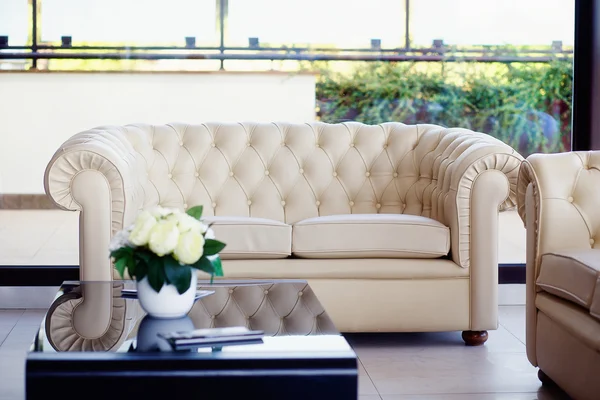 Poltrona sofá de couro branco & flores na mesa — Fotografia de Stock