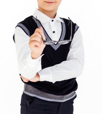 Beyaz gömlekli ve siyah yelekli bir çocuk elinde bardaklarla ayakta duruyor. Fotoğraf.