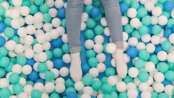 多色のプラスチックボールの中に横になり 元気に足を広げています 良い気分と自由の感覚 ビデオ — ストック動画