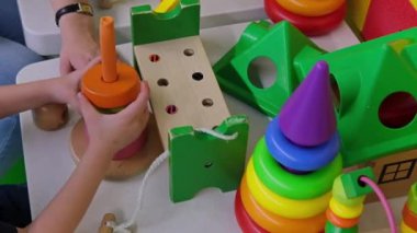 çocukluk, gelişme, beceriler, hareketlilik oyunları - küçük bebek elleri piramidin üzerine plastik oyuncaklar takıyor. Video