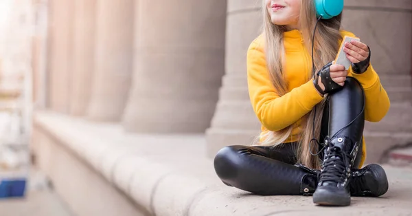Dziewczyna Żółtym Swetrze Skórzane Spodnie Rękawiczki Pozujące Niebieskich Słuchawkach Ulicy — Zdjęcie stockowe