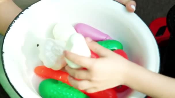 ママと男の子が遊んでいる ママは皿を手に持っていて 男の子はおもちゃのプラスチック野菜を入れています 高品質のフルHd映像 — ストック動画