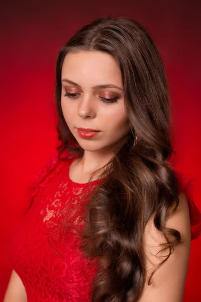 Portrait of young brunette girl in a red dress on red background — Stock Photo, Image