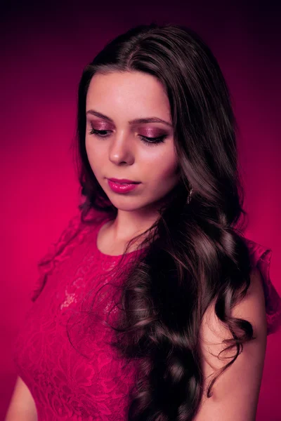 Portrait of young brunette girl in a red dress on red background — Stock Photo, Image