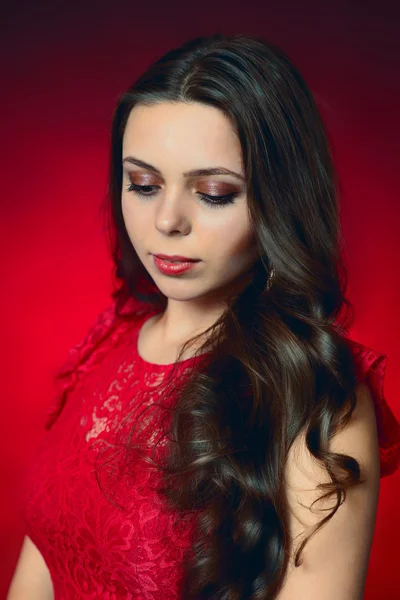 Retrato de jovem morena em um vestido vermelho no fundo vermelho — Fotografia de Stock