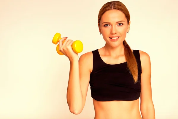 stock image A woman holding a yellow dumbbell. Engaged in fitness.