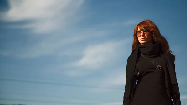 Schöne junge Frau in schwarzem Kleid und Brille posiert über bl — Stockfoto