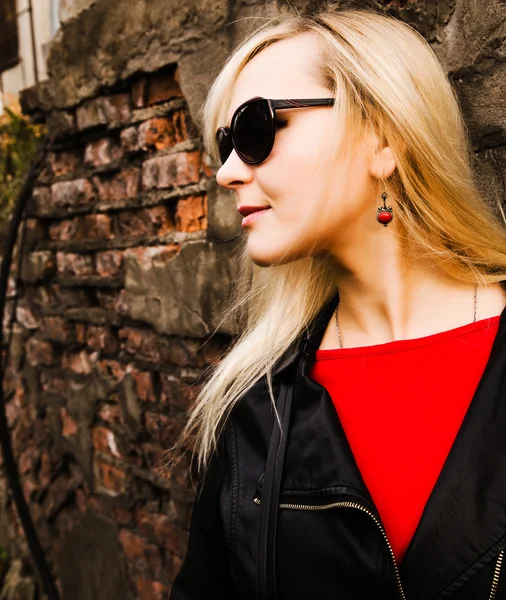 Mooie jonge vrouw in zwart lederen jas en zonnebril pos — Stockfoto